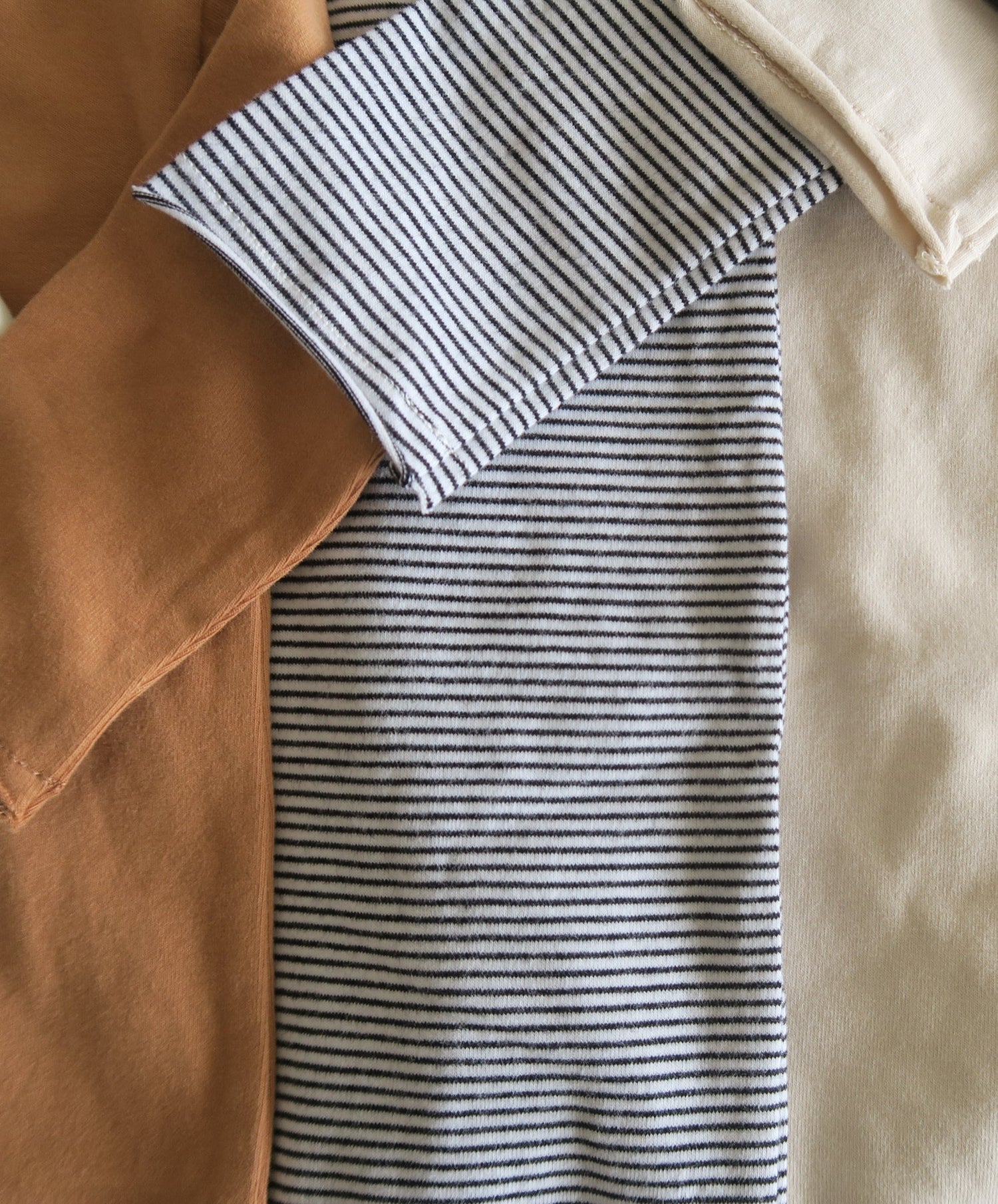 Brown, black and white striped and beige organic cotton textile side by side, OiOiOi